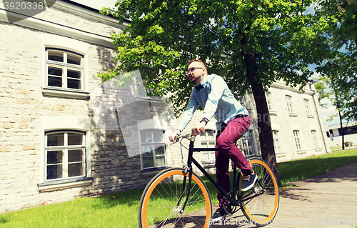 Image of happy young hipster man riding fixed gear bike