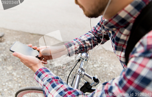 Image of hipster man in earphones with smartphone and bike