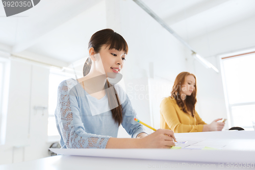 Image of architect woman with blueprint writing at office