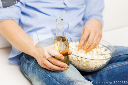 Image of close up of man with popcorn and beer at home