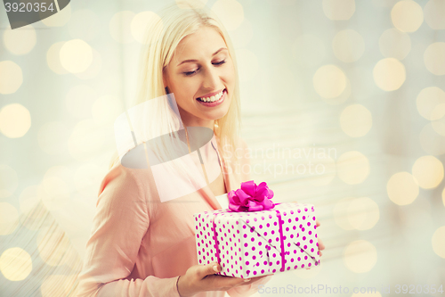 Image of smiling woman with gift box over holidays lights