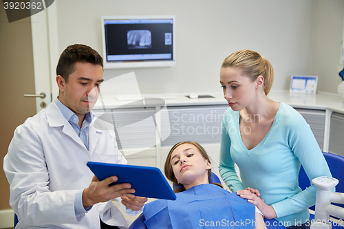 Image of dentist showing tablet pc to girl and her mother