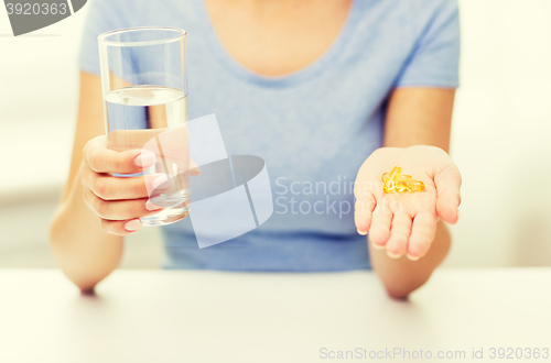 Image of close up of woman hands with capsules and water