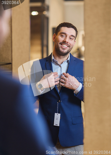 Image of man trying jacket on at mirror in clothing store