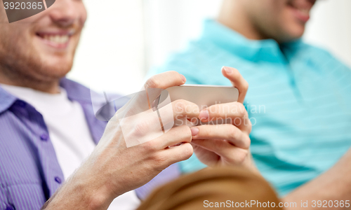 Image of close up of happy friends with smartphones at home