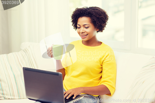 Image of happy african american woman with laptop at home