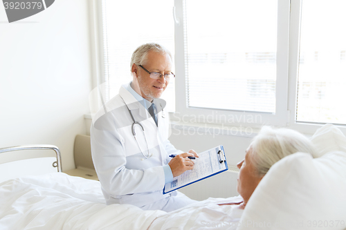 Image of senior woman and doctor with clipboard at hospital