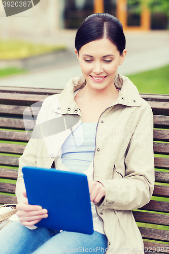 Image of woman with tablet pc sitting on bench in park