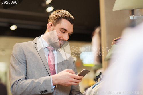 Image of man in suit with smartphone at clothing store