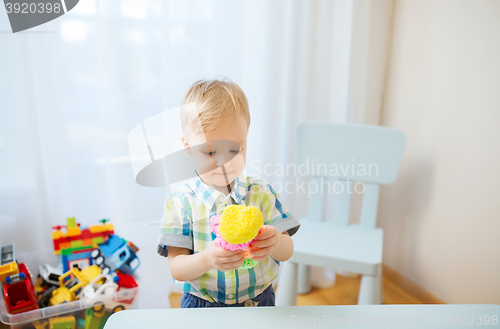 Image of happy little baby boy with ball clay at home