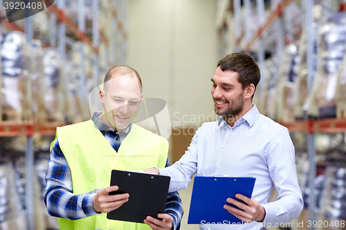 Image of worker and businessmen with clipboard at warehouse