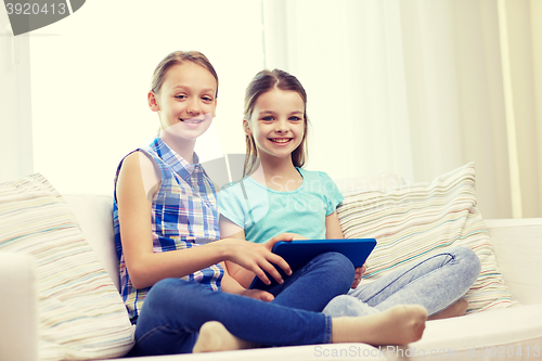 Image of happy girls with tablet pc sitting on sofa at home