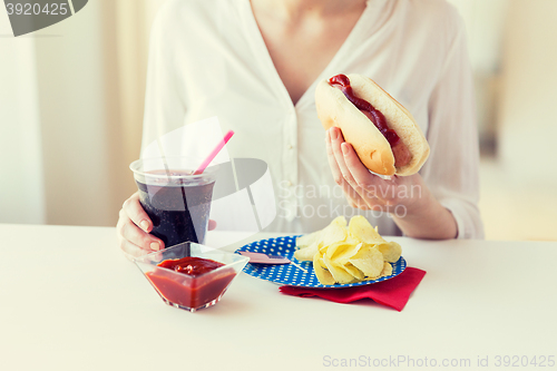 Image of close up of woman eating hot dog with cola