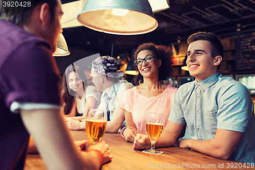 Image of happy friends drinking beer and talking at bar