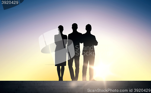 Image of business people silhouettes on stairs over sun