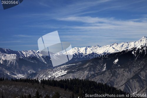 Image of View on snowy mountains in sun windy day