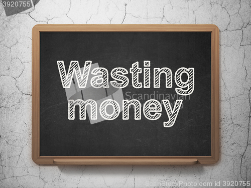 Image of Money concept: Wasting Money on chalkboard background