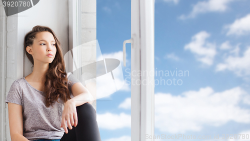 Image of sad pretty teenage girl sitting on windowsill