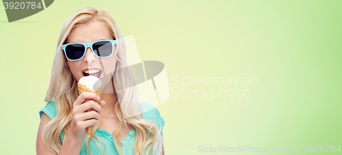 Image of happy young woman in sunglasses eating ice cream