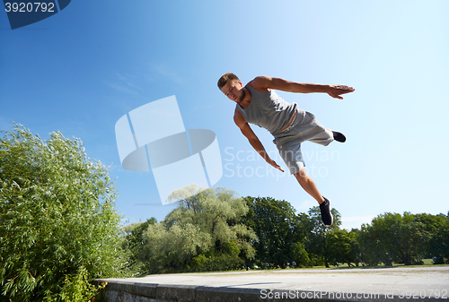 Image of sporty young man jumping in summer park