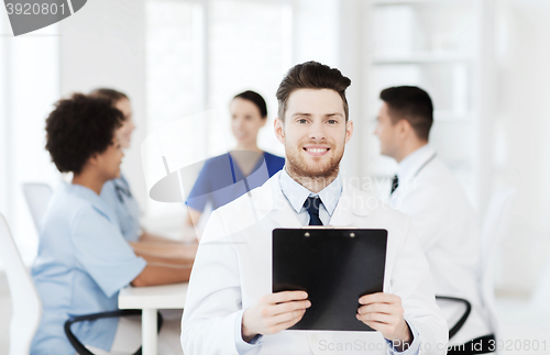 Image of happy doctor with tablet pc over team at clinic