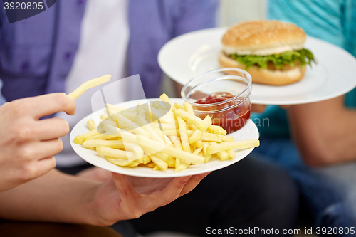 Image of close up of male hands with fast food on plates