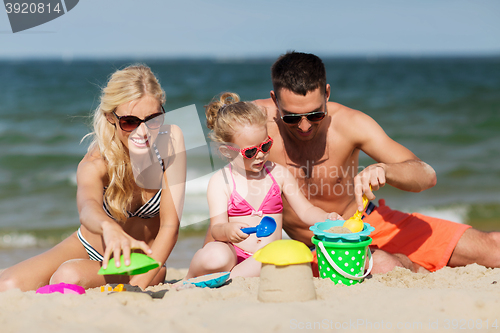 Image of happy family playing with sand toys on beach