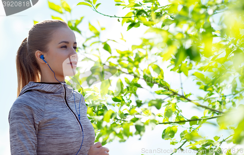 Image of happy woman with earphones running in city