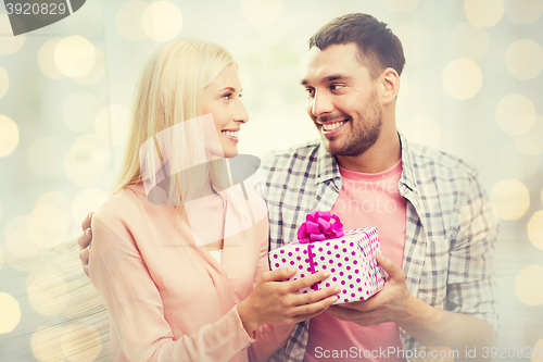 Image of happy man giving woman gift box over lights