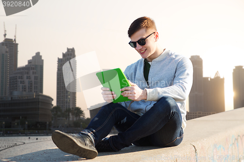 Image of happy young man with tablet pc in city
