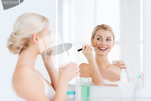 Image of woman with makeup brush and powder at bathroom