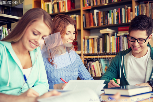 Image of happy students writing to notebooks in library