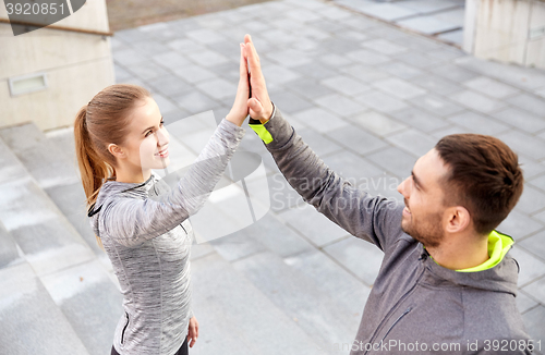 Image of smiling couple making high five on city street