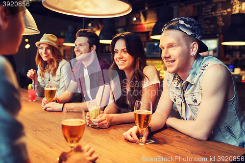 Image of happy friends with drinks talking at bar or pub