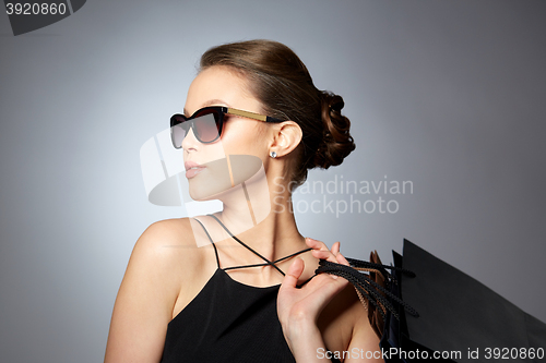 Image of happy woman in black sunglasses with shopping bags