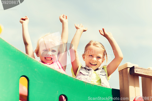Image of happy girls waving hands on children playground