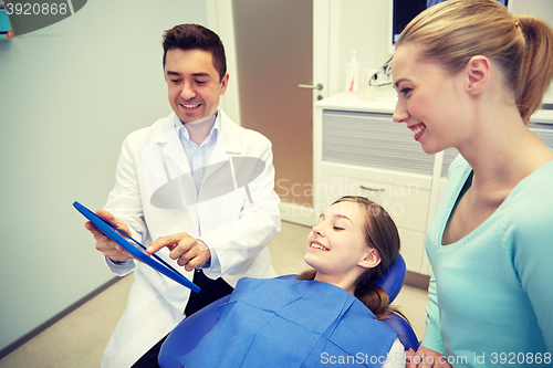 Image of dentist showing tablet pc to girl and her mother
