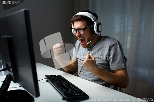 Image of man in headset playing computer video game at home