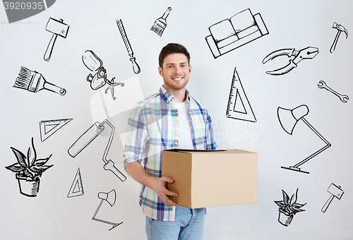 Image of smiling young man with cardboard box at home