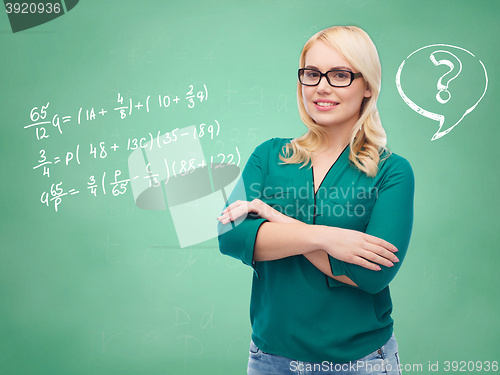 Image of happy woman in eyeglasses over school blackboard