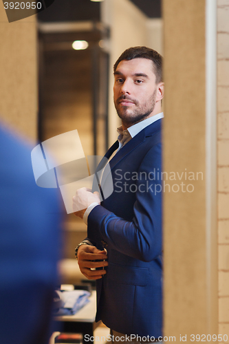 Image of man trying jacket on at mirror in clothing store