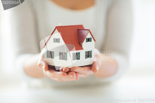 Image of close up of hands holding house or home model