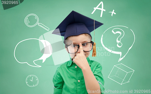 Image of boy in bachelor hat and eyeglasses over blackboard