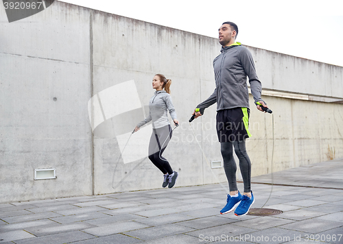 Image of man and woman exercising with jump-rope outdoors