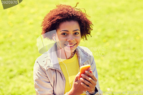 Image of happy african woman with smartphone and earphones