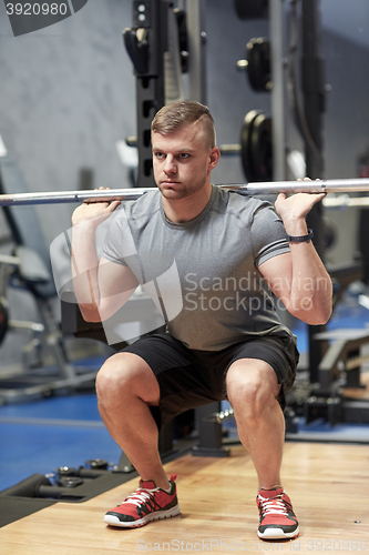 Image of young man flexing muscles with barbell in gym