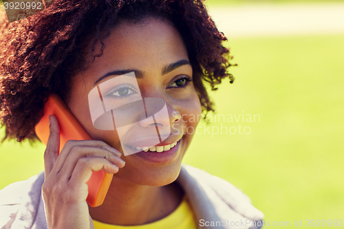 Image of happy african woman calling on smartphone outdoors