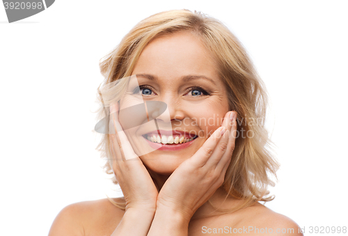 Image of smiling woman with bare shoulders touching face