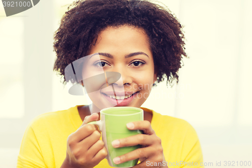 Image of happy african american woman drinking from tea cup