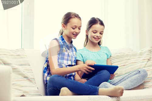 Image of happy girls with tablet pc sitting on sofa at home